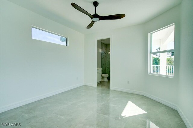 unfurnished bedroom featuring multiple windows, baseboards, and ensuite bathroom