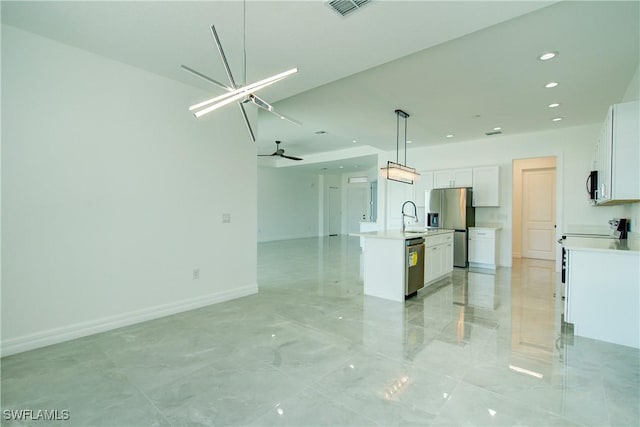 kitchen with appliances with stainless steel finishes, open floor plan, a sink, and light countertops