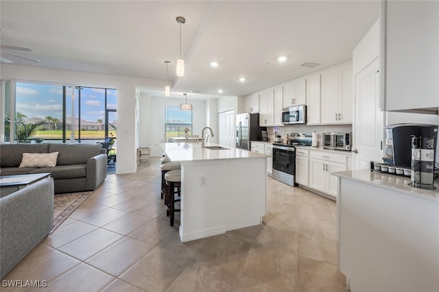 kitchen featuring a sink, open floor plan, appliances with stainless steel finishes, white cabinets, and light countertops