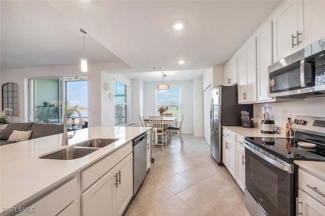 kitchen with white cabinets, stainless steel appliances, light countertops, and a sink