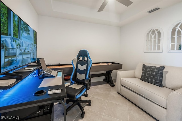 office with tile patterned floors, visible vents, a raised ceiling, and ceiling fan