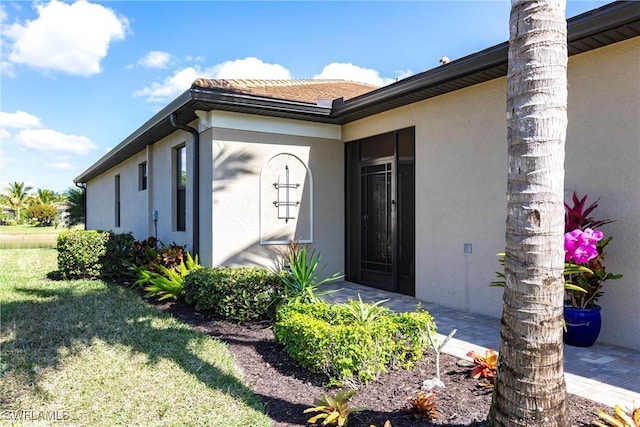 entrance to property with a lawn and stucco siding