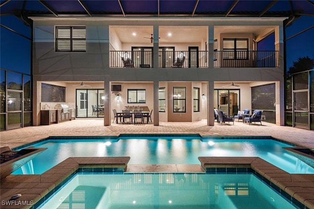 rear view of house with a lanai, exterior kitchen, stucco siding, a balcony, and a patio