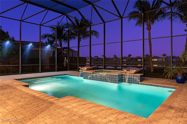 pool at twilight with glass enclosure, a patio, and a pool with connected hot tub