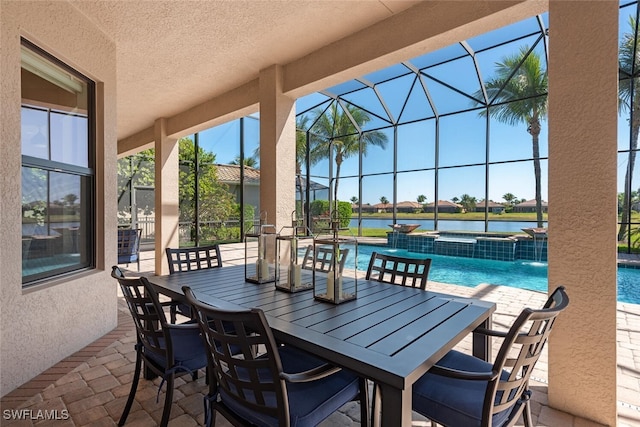 view of patio with glass enclosure, a pool with connected hot tub, outdoor dining area, and a water view