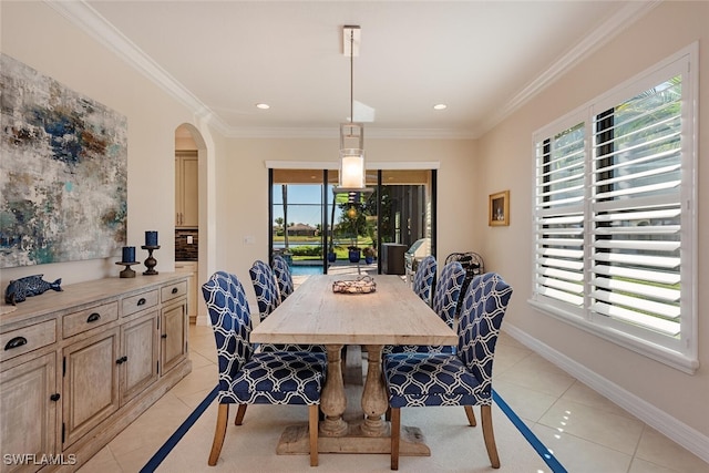 dining area with light tile patterned floors, baseboards, arched walkways, and crown molding