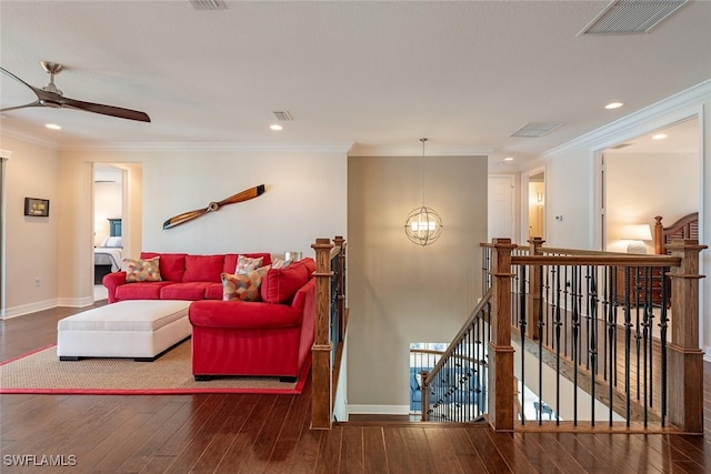 living area with hardwood / wood-style flooring, ceiling fan with notable chandelier, baseboards, and ornamental molding