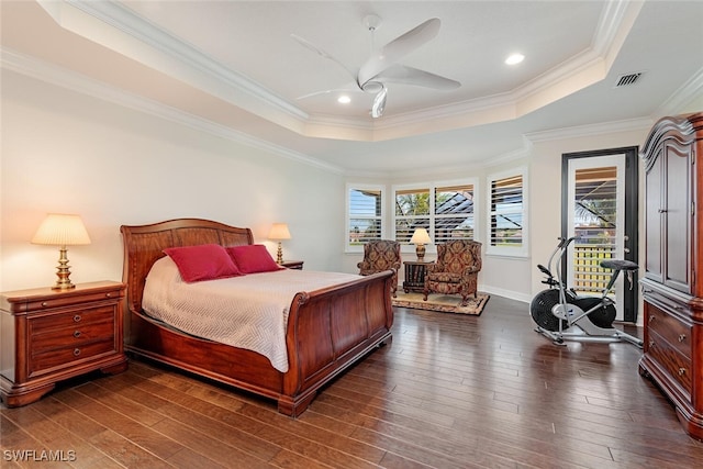 bedroom featuring dark wood finished floors, multiple windows, and a tray ceiling