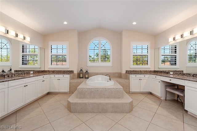 bathroom with tile patterned flooring, lofted ceiling, a bath, and vanity