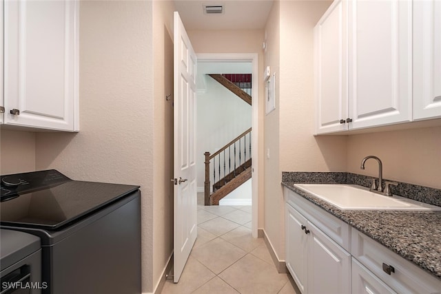 washroom with visible vents, a sink, light tile patterned flooring, cabinet space, and separate washer and dryer