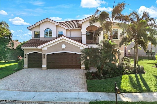 mediterranean / spanish-style house with stucco siding, a front lawn, decorative driveway, a garage, and a tiled roof