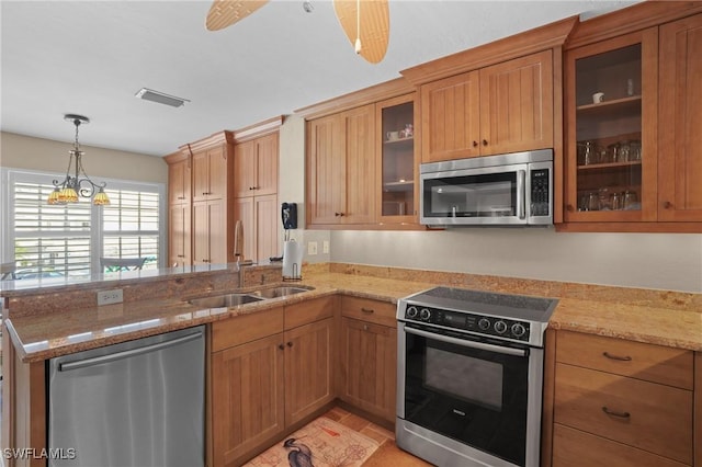 kitchen featuring a sink, a peninsula, light stone counters, and stainless steel appliances