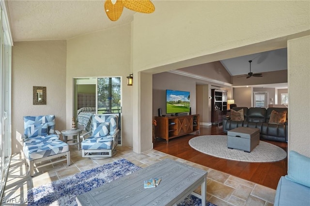 living room featuring a ceiling fan and high vaulted ceiling