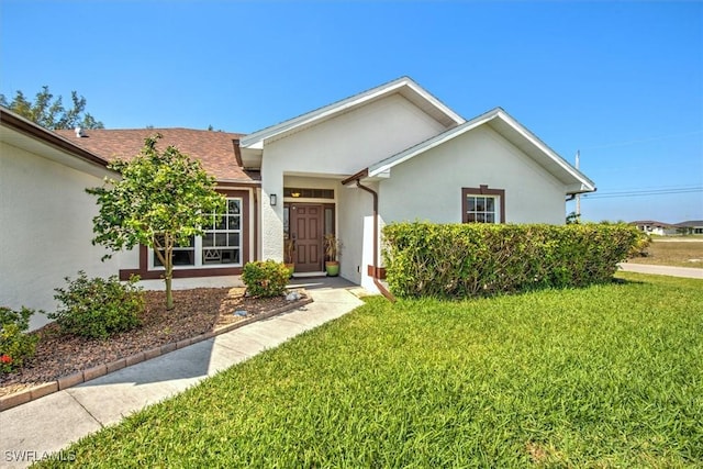 ranch-style house with roof with shingles, a front yard, and stucco siding