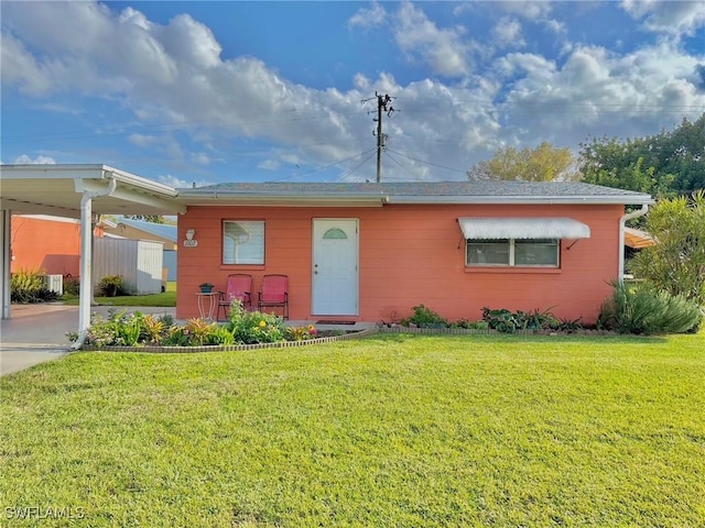 view of front of house with an attached carport, concrete driveway, and a front lawn