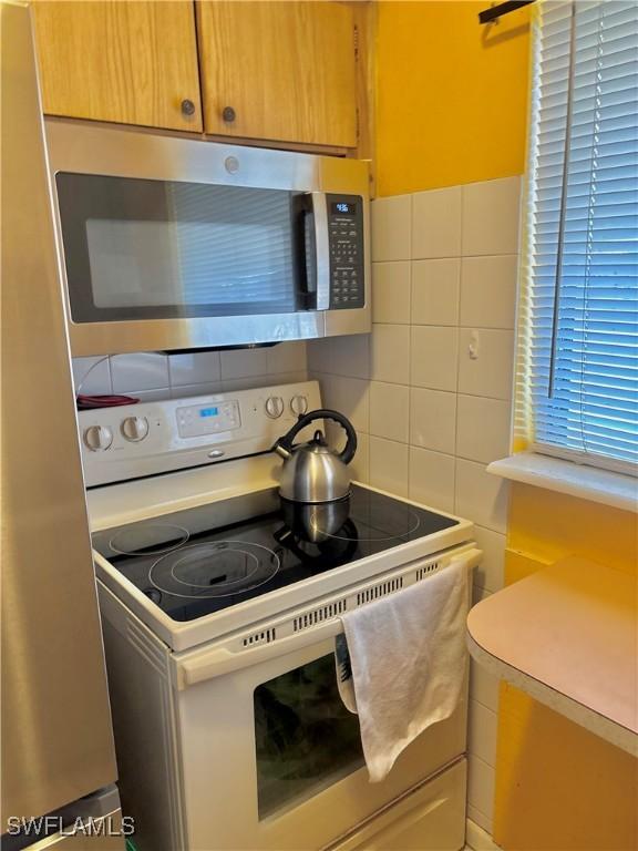 1102 Broad St N, Lehigh Acres, FL 33936 - kitchen with electric range, light countertops, stainless steel microwave, tile walls, and tasteful backsplash