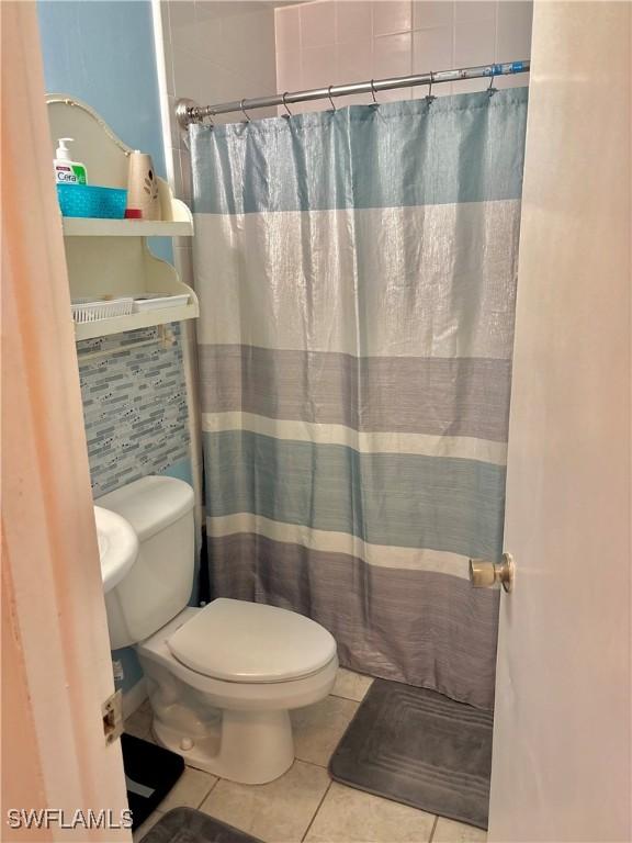 1102 Broad St N, Lehigh Acres, FL 33936 - bathroom featuring a shower with curtain, toilet, and tile patterned flooring
