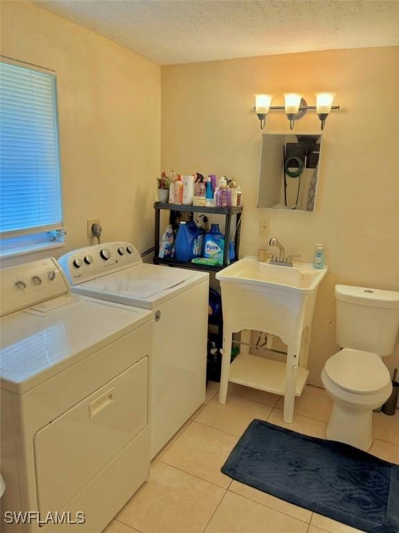 1102 Broad St N, Lehigh Acres, FL 33936 - clothes washing area with laundry area, light tile patterned flooring, washing machine and dryer, and a textured ceiling