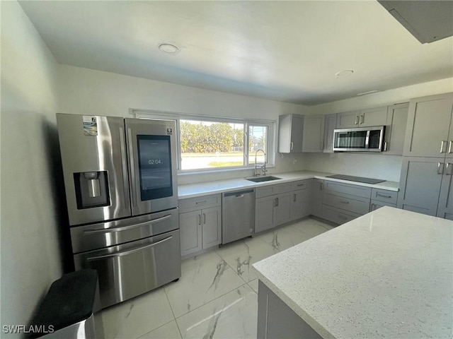 kitchen with marble finish floor, stainless steel appliances, a sink, and gray cabinetry