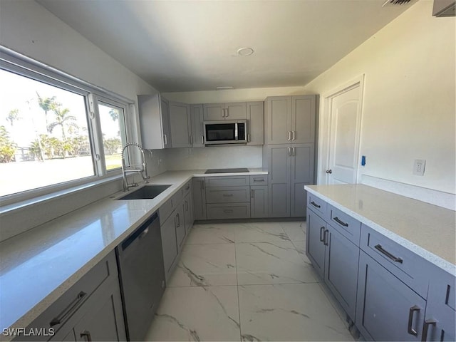 kitchen with dishwashing machine, stainless steel microwave, marble finish floor, gray cabinets, and a sink