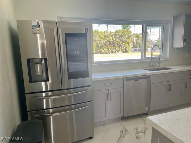 kitchen featuring marble finish floor, gray cabinets, stainless steel appliances, light countertops, and a sink