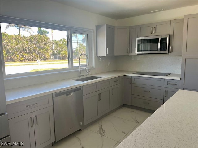 kitchen featuring marble finish floor, stainless steel appliances, gray cabinets, and a sink