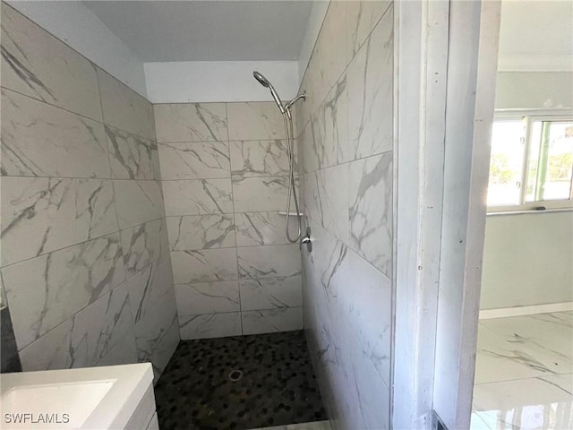 bathroom with marble finish floor and a tile shower