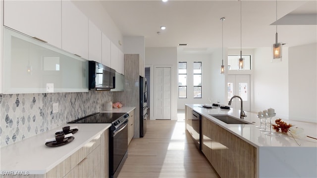 kitchen featuring stainless steel appliances, a sink, light countertops, backsplash, and modern cabinets