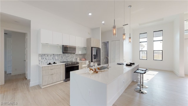 kitchen with appliances with stainless steel finishes, modern cabinets, a sink, and decorative backsplash