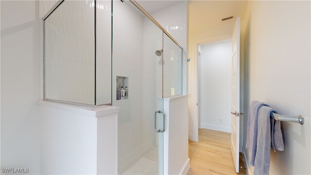 full bath with a shower stall, baseboards, and wood finished floors