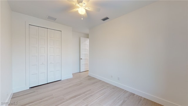 unfurnished bedroom with baseboards, a closet, visible vents, and light wood-style floors