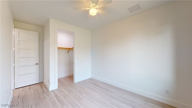 unfurnished bedroom featuring a closet, visible vents, light wood-style flooring, ceiling fan, and baseboards