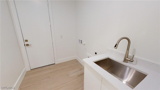 washroom featuring washer hookup, light wood finished floors, a sink, electric dryer hookup, and laundry area