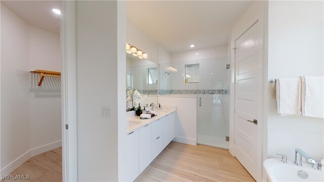 bathroom featuring a walk in closet, a shower stall, vanity, a tub, and baseboards