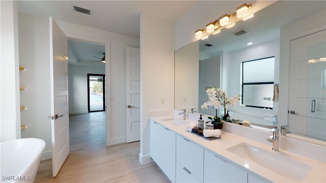 bathroom featuring visible vents, a sink, a freestanding bath, and wood finished floors