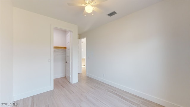 unfurnished bedroom featuring a walk in closet, a closet, visible vents, light wood-type flooring, and baseboards