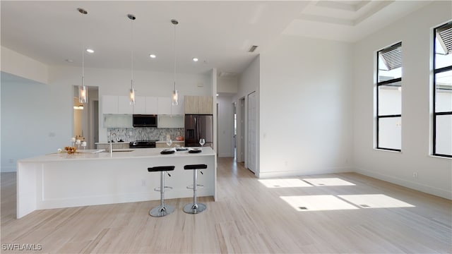 kitchen featuring a sink, light countertops, appliances with stainless steel finishes, decorative backsplash, and modern cabinets