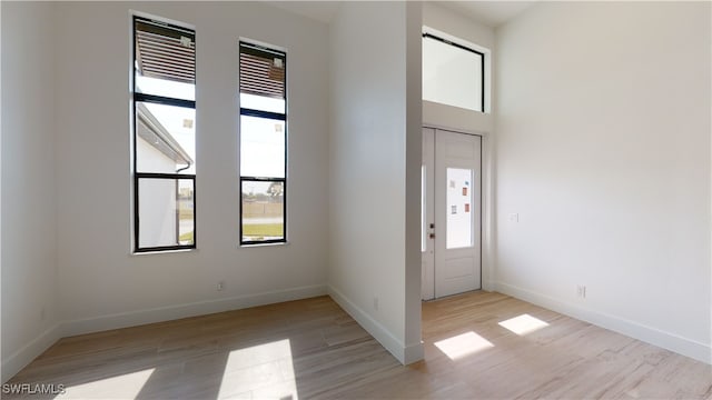 entryway featuring light wood-type flooring, a high ceiling, and baseboards