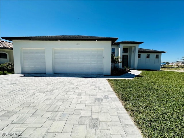 view of front of home with an attached garage, a front yard, decorative driveway, and stucco siding