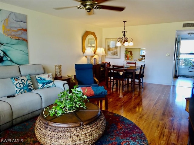 living room featuring visible vents, wood finished floors, and ceiling fan with notable chandelier