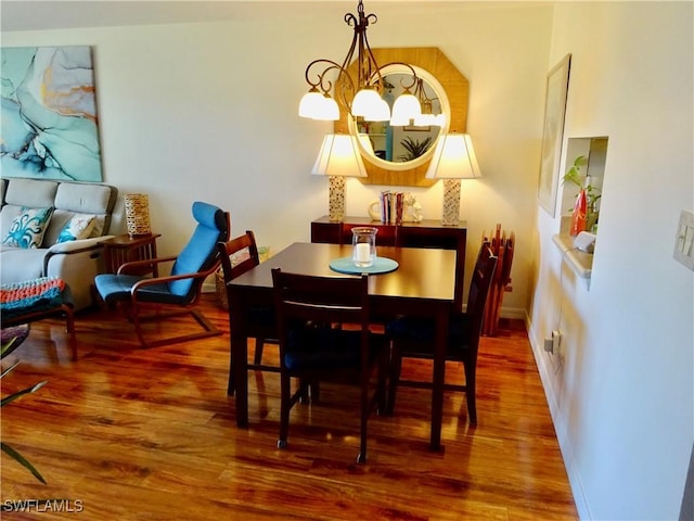 dining area featuring an inviting chandelier, baseboards, and wood finished floors