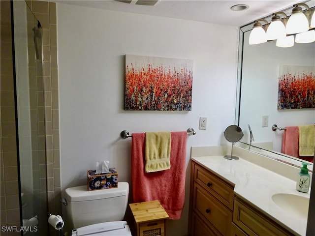 bathroom featuring toilet, tiled shower, and vanity