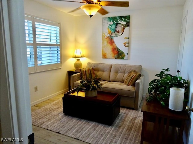 living area with a ceiling fan and baseboards