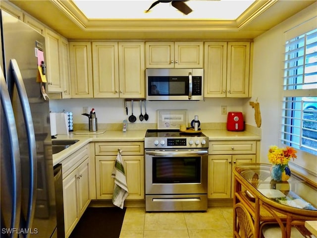 kitchen with crown molding, light tile patterned floors, stainless steel appliances, light countertops, and ceiling fan