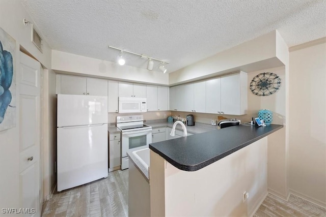 kitchen with white cabinets, white appliances, light wood-style floors, and a peninsula