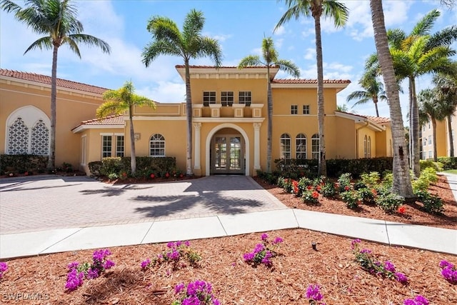 view of front facade with a tile roof, french doors, and stucco siding