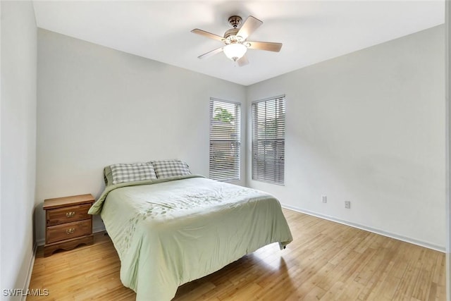 bedroom with light wood-style flooring, baseboards, and ceiling fan