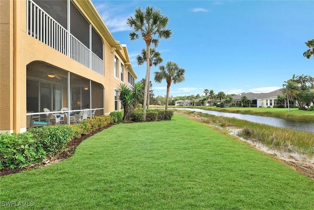 view of yard featuring a sunroom, a water view, and a balcony