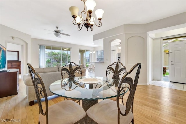 dining area with light wood finished floors, baseboards, and ceiling fan with notable chandelier