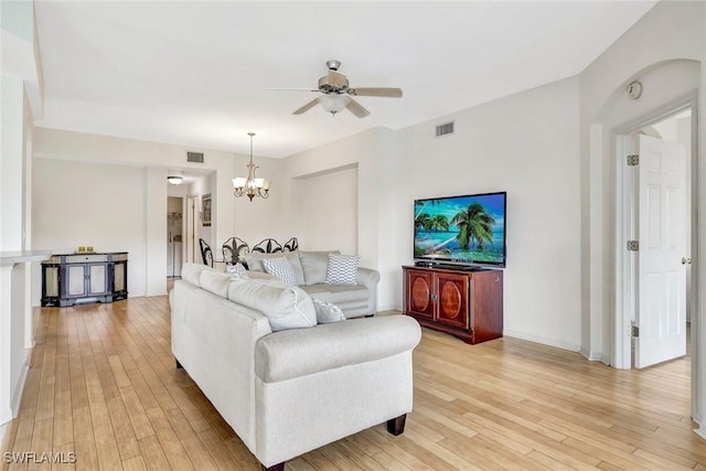 living room with ceiling fan with notable chandelier, baseboards, visible vents, and light wood-style floors